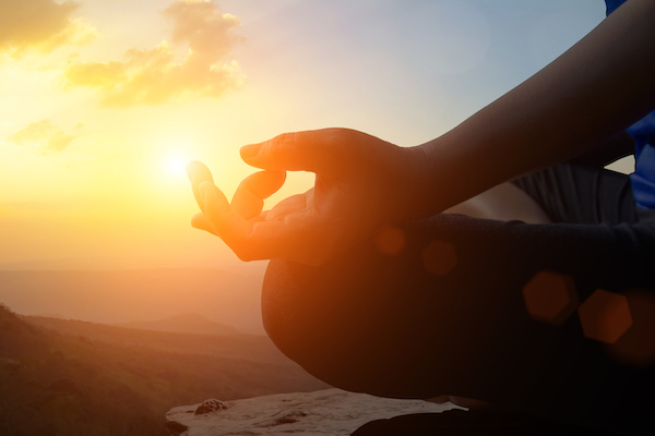 Young women meditate while doing yoga meditation, spiritual mental health practice with silhouette of lotus pose having peaceful mind relaxation on mountain outdoor with sunset golden heavenly sky.