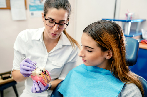 Dentist explaining what dental cavity looks to a patient  sitting on a dentist's chair