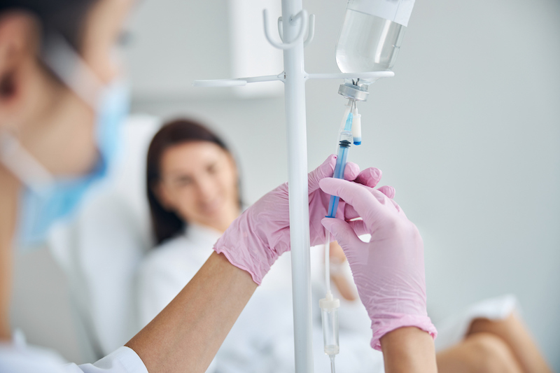 Experienced Caucasian heath care worker preparing a dark-haired female patient for the intravenous vitamin therapy