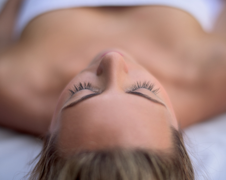 Young woman relaxing at the spa lying on the bed - beauty concepts